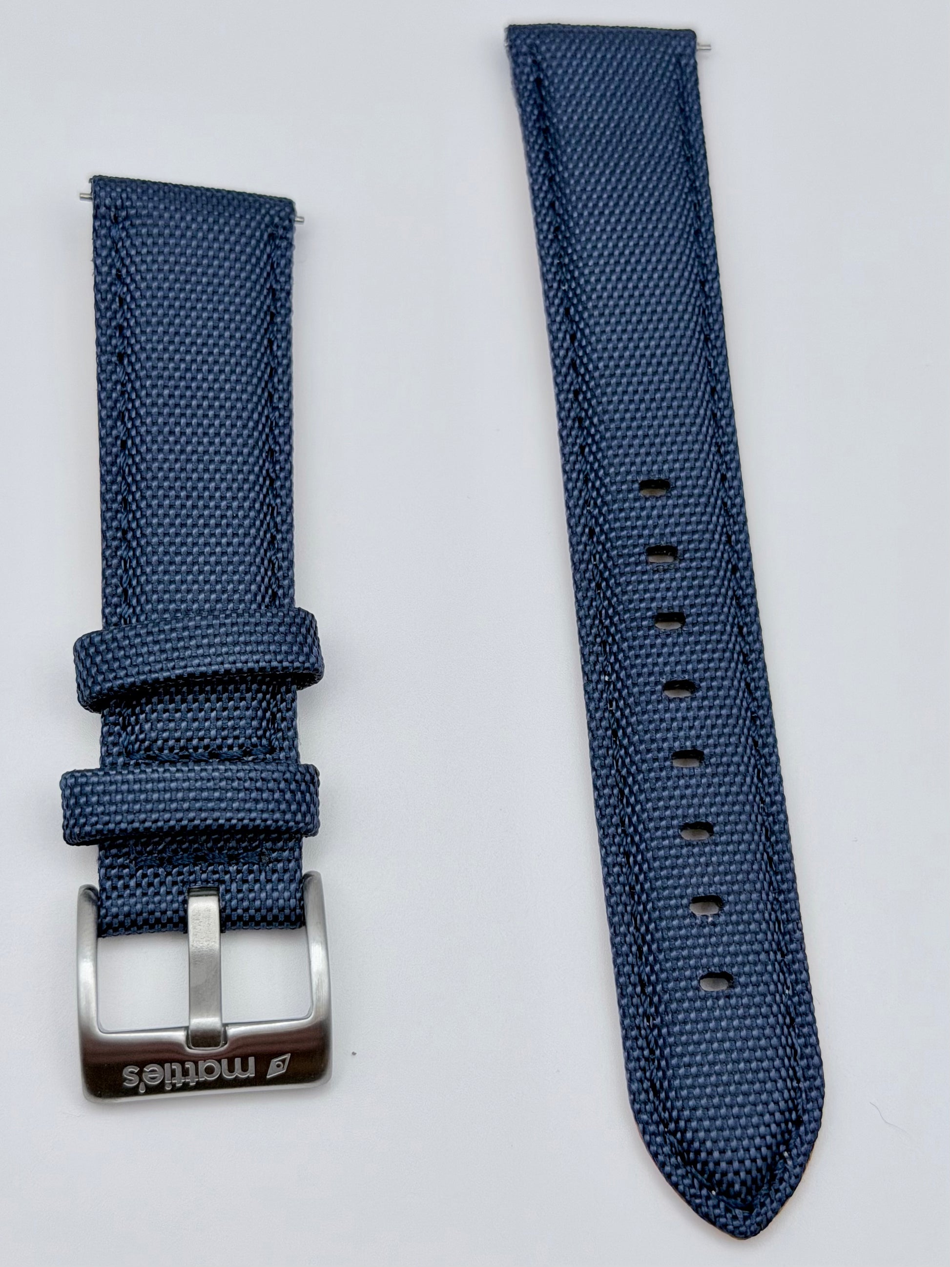 A navy blue woven nylon watch strap  featuring a silver-tone metal buckle engraved with the brand name 'Mattie's'.
